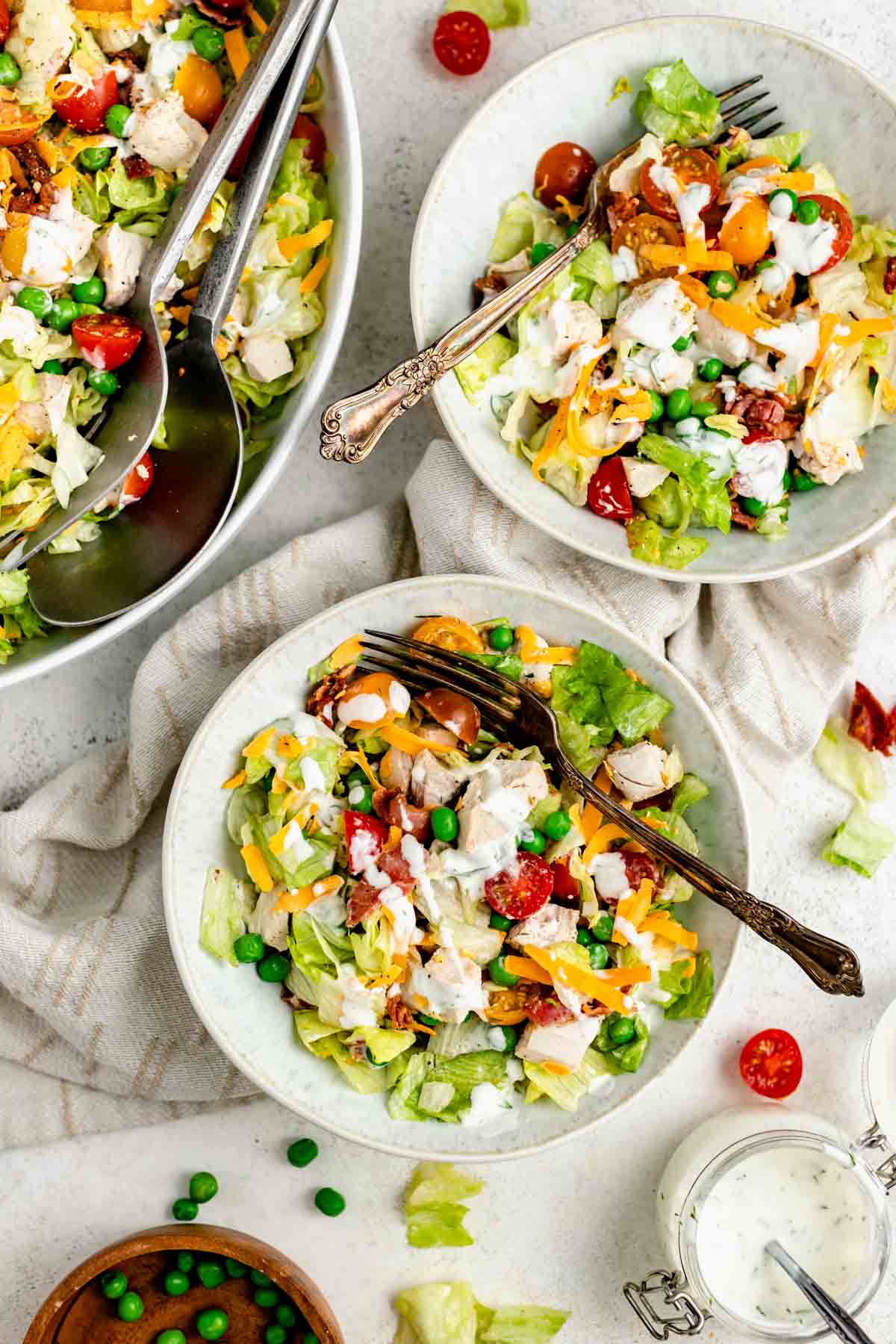 a couple of bowls full of the chopped salad with chicken with additional dressing drizzled on top