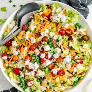 chopped salad with chicken in a bowl with tongs