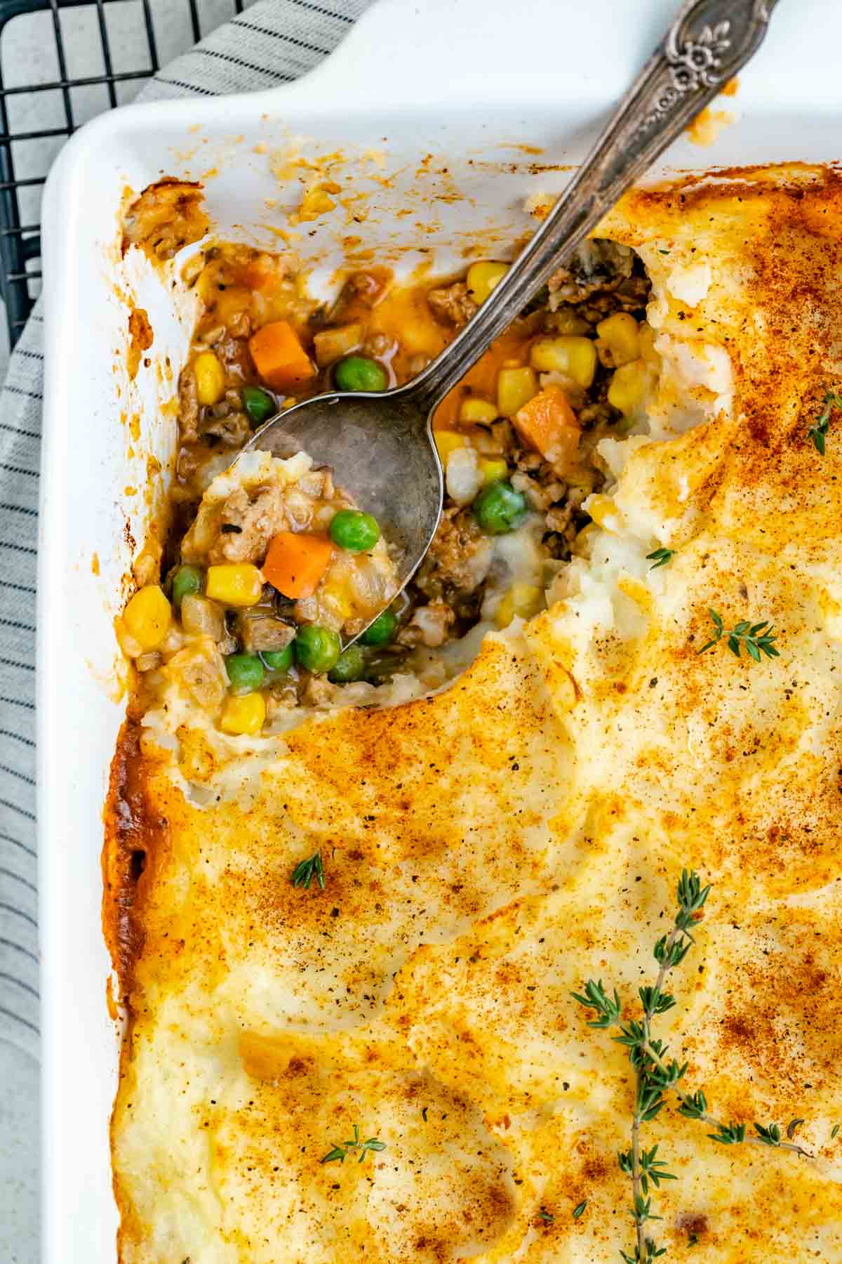 overhead shot of a spoon scooping up some shepherd's pie out of the corner of the casserole dish