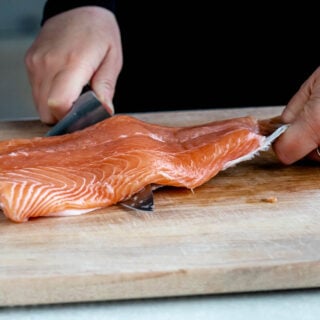 removing salmon skin with a chef's knife before cooking it