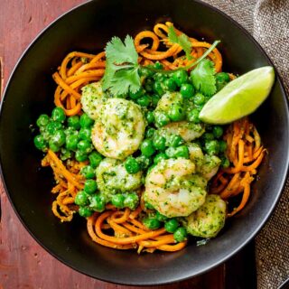 close up of the noodles with shrimp and peas in a black bowl from overhead