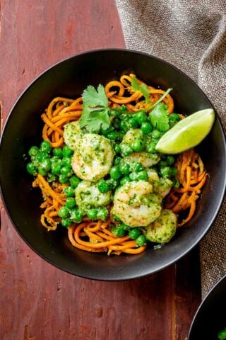 close up of the noodles with shrimp and peas in a black bowl from overhead