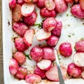 Close up overhead photo of roasted radishes in white dish with a spoon