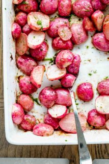Close up overhead photo of roasted radishes in white dish with a spoon