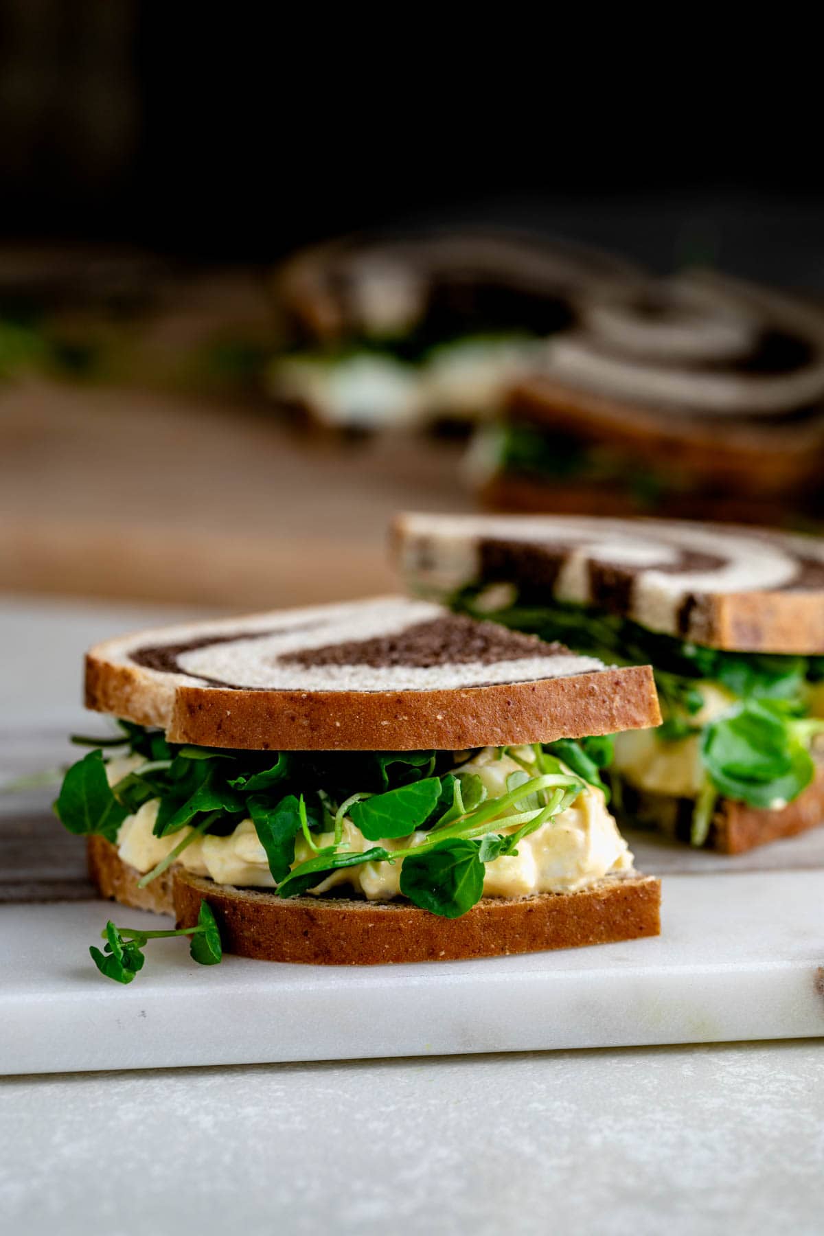 a watercress sandwich with egg salad on marbled rye bread cut in half