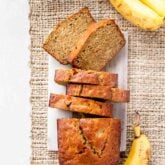 whole wheat banana bread cut into slices with whole bananas surrounding