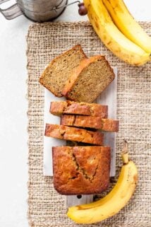 whole wheat banana bread cut into slices with whole bananas surrounding