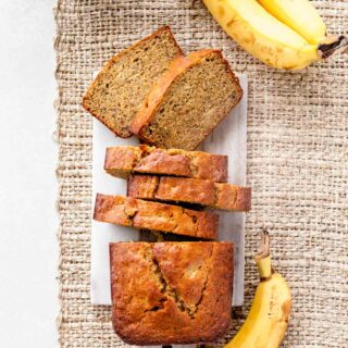 whole wheat banana bread sliced up with bananas around