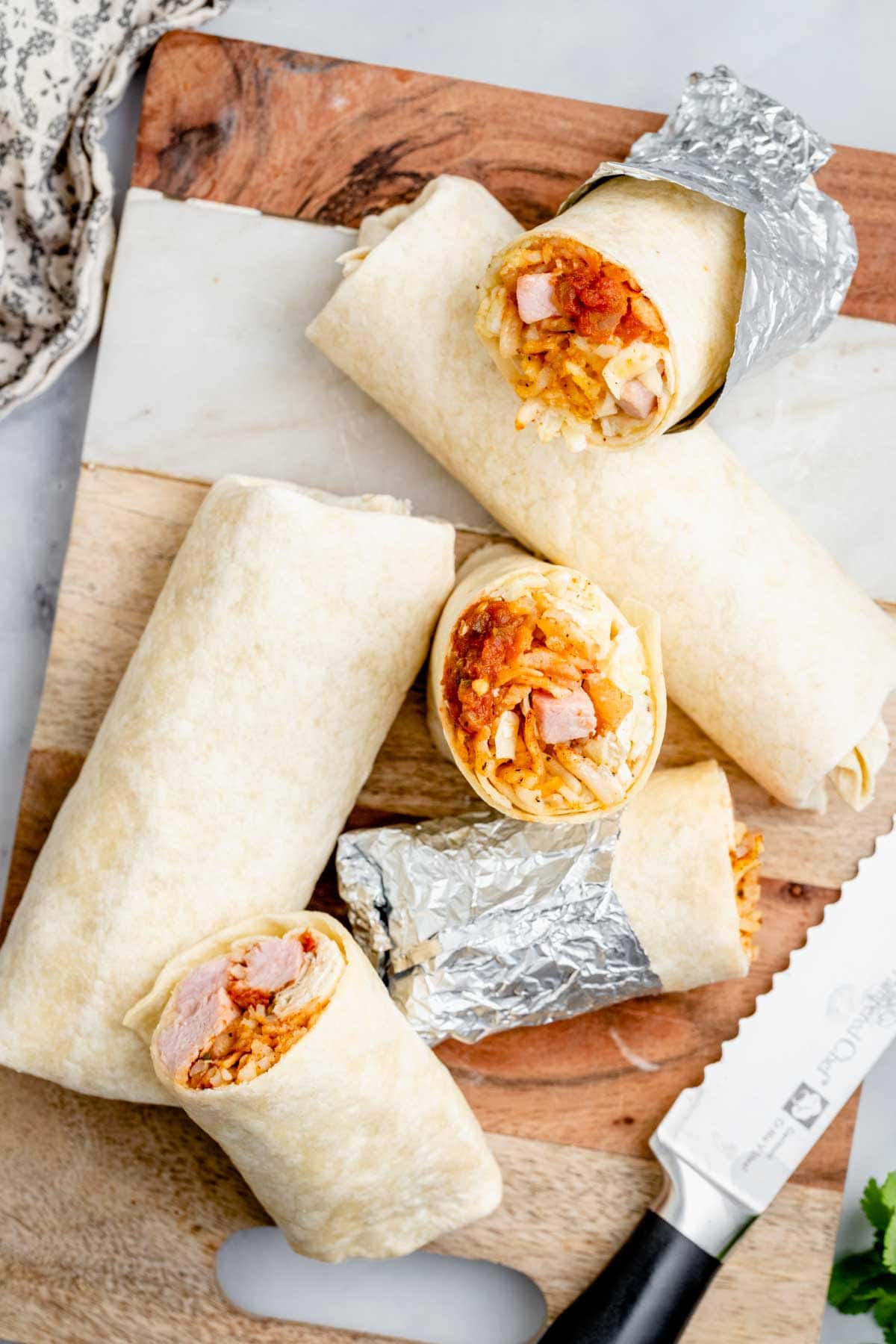 finished burritos on cutting board with 2 burritos cut in half