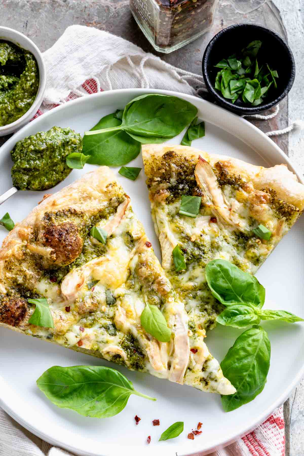 two slices of pizza on a white plate garnished with fresh basil