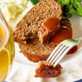 two slices of barbecued beef meatloaf with barbecue sauce on them, with mashed potatoes and broccoli