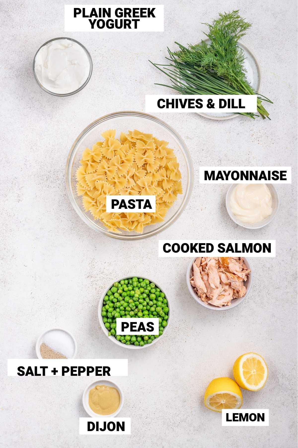 ingredients for salmon pasta salad including greek yogurt, cooked salmon, chives and dill, farfalle pasta, mayonnaise, peas, lemon, dijon, and salt and pepper.