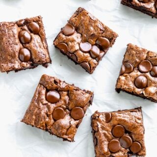 whole wheat brownies cut into squares on a white piece of parchment