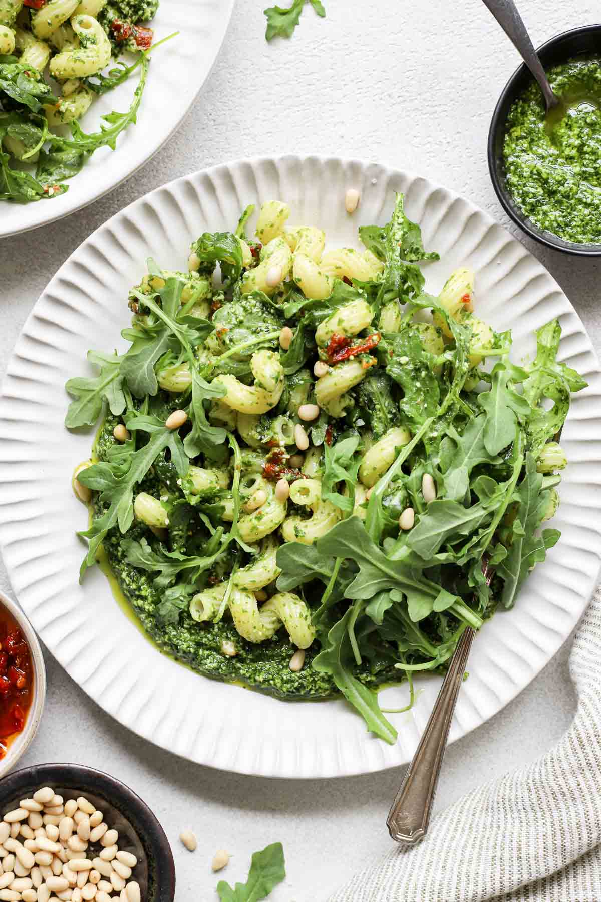 close up view of arugula pasta in circular white plate with fork