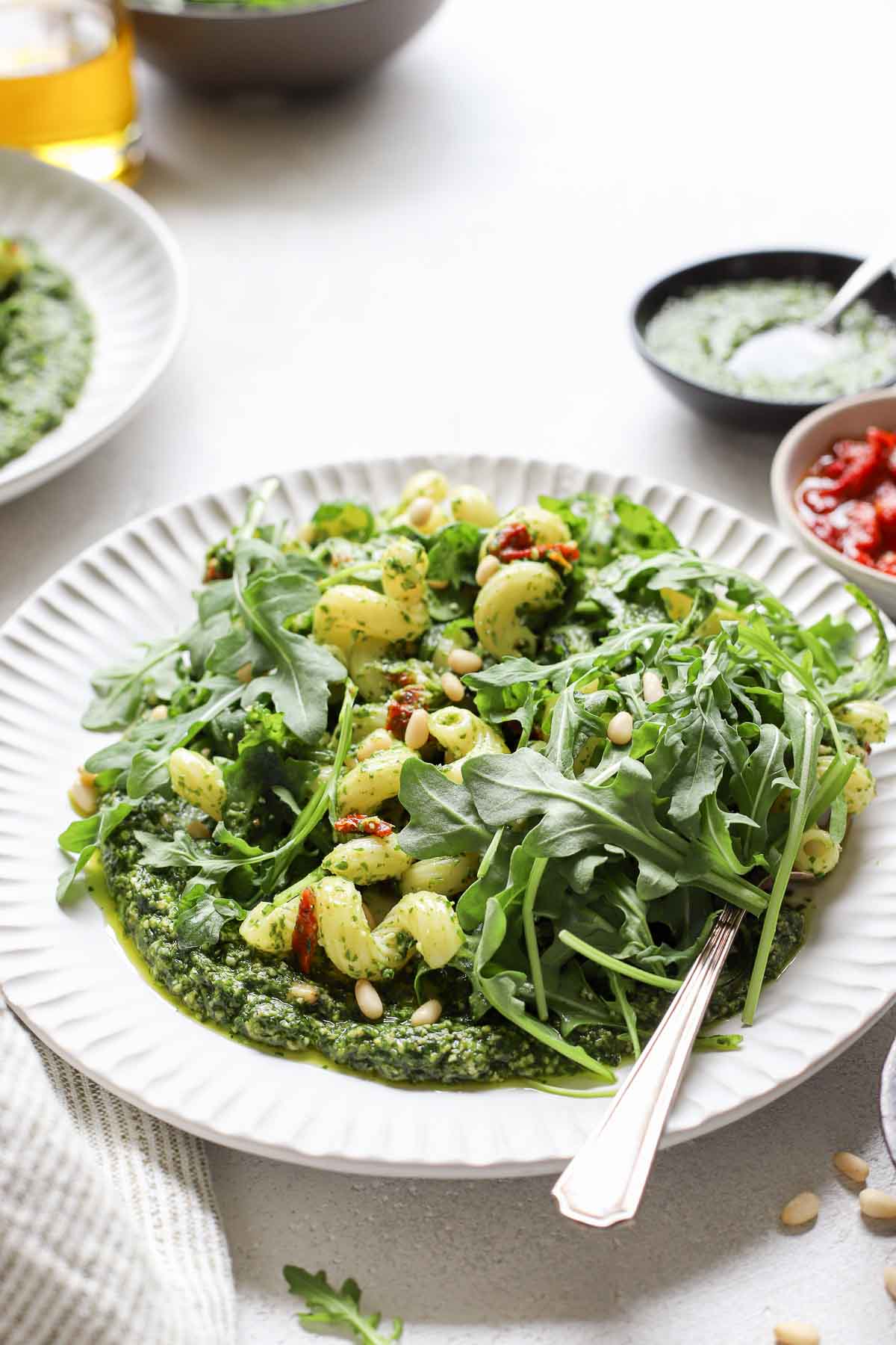 peppery arugula pasta in circular white dish with fork in the dish