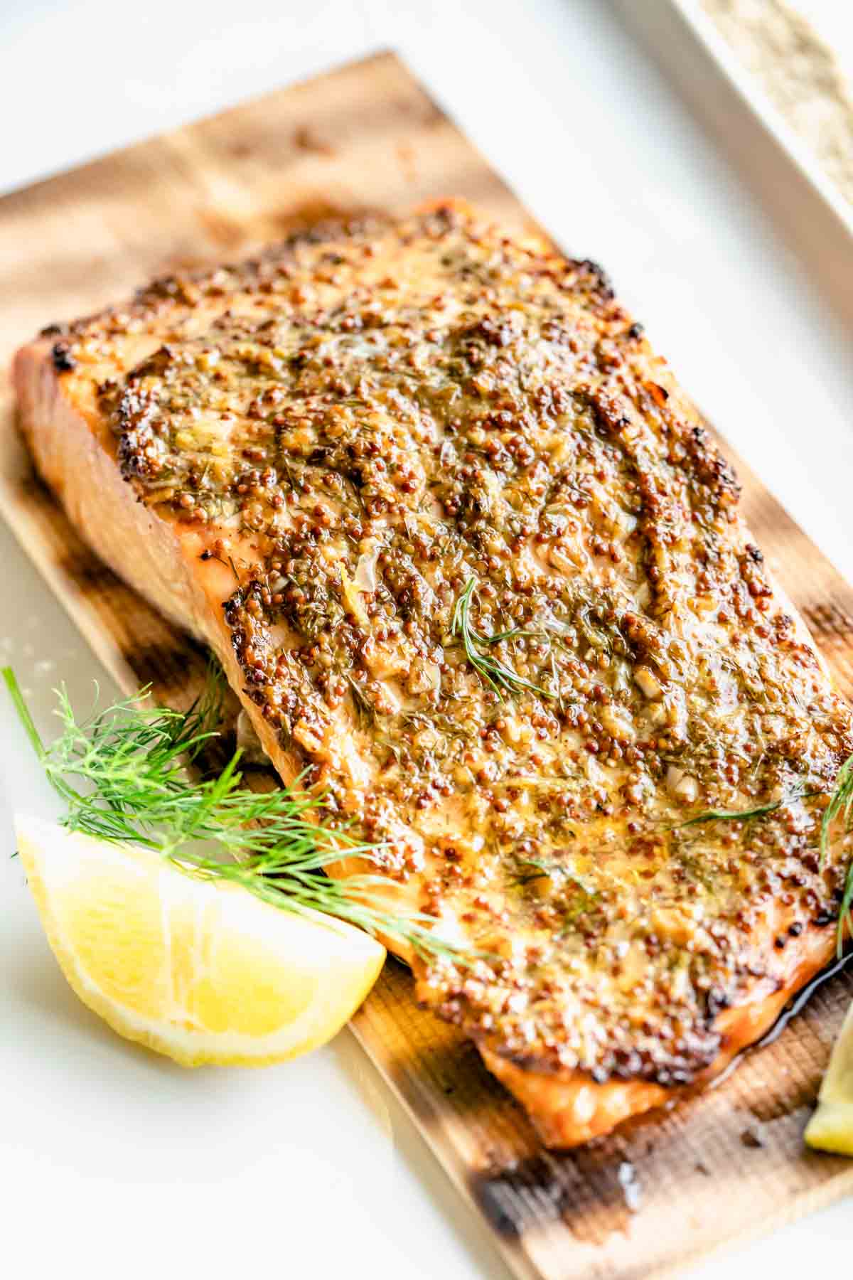 the grilled salmon on the plank with mustard rub on it
