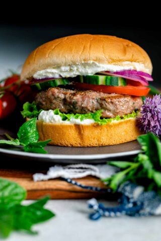 very close up side view of the burger on a bun on a black plate