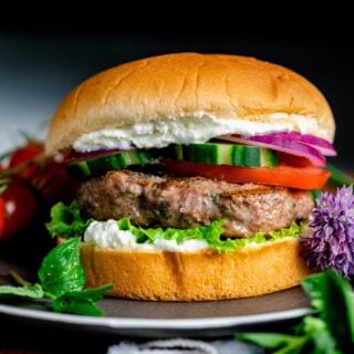lamb burgers on bun with cucumbers, tomatoes and red onions
