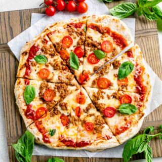 grilled pizza on wooden board sliced into triangle pieces