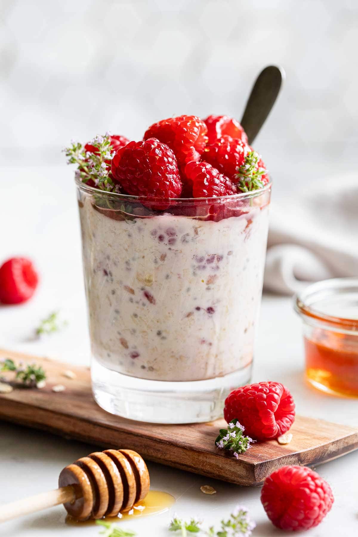 side view of overnight oats with raspberries on a wooden board. Oats topped with fresh raspberries.