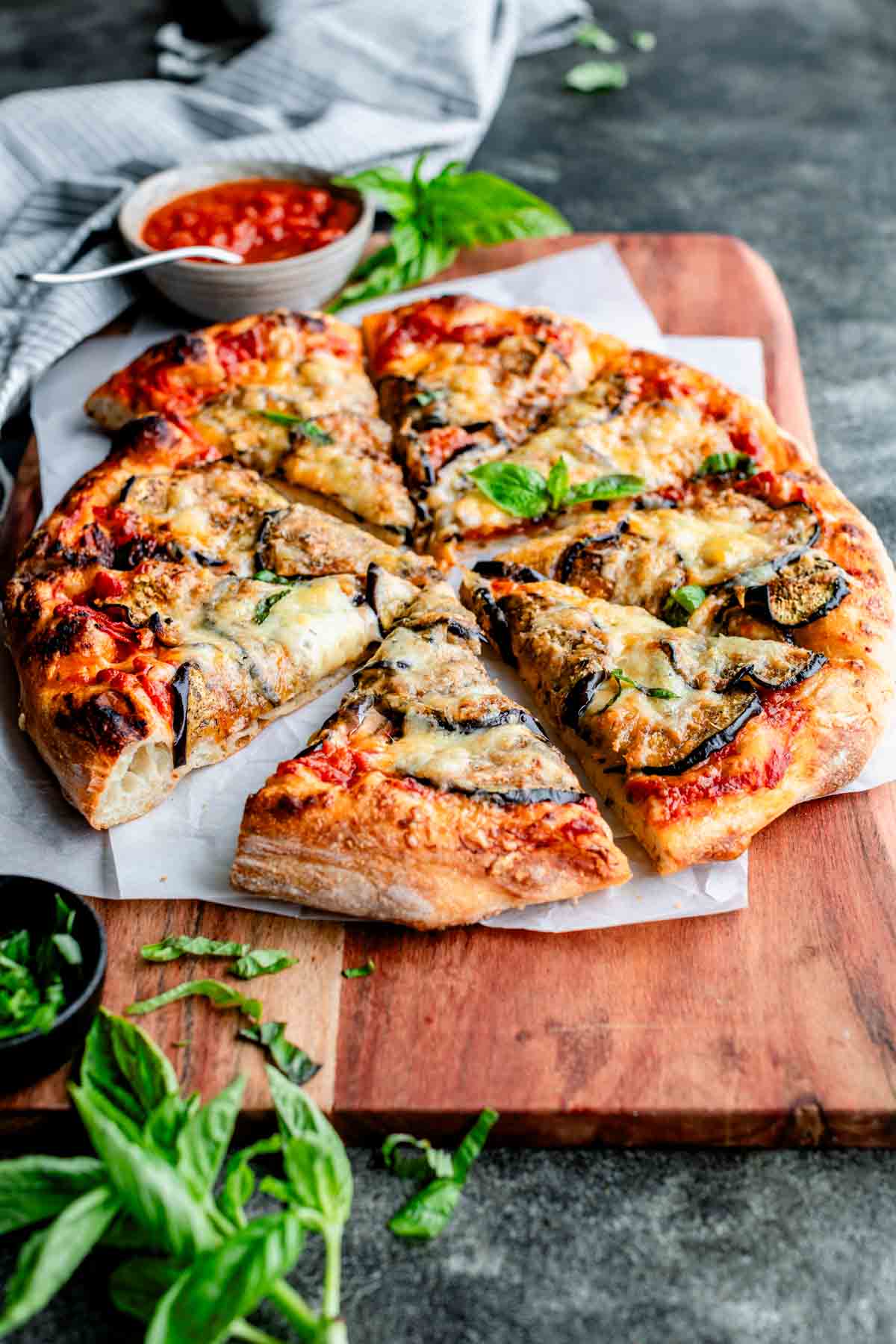 baked homemade pizza with eggplant on cutting board and cut into triangles