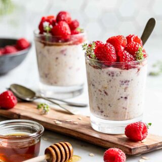 overnight oats with raspberries on a wooden plank, topped with fresh raspberries