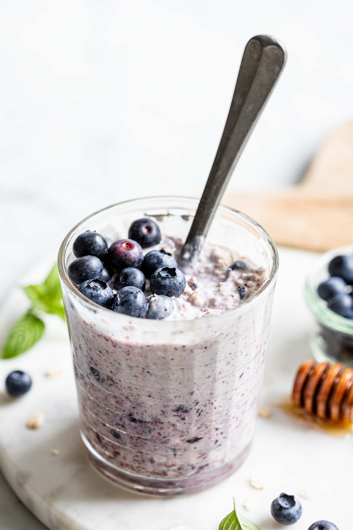 one of the jars of overnight oats after it has been refrigerated and then mixed with a spoon and topped with fresh blueberries