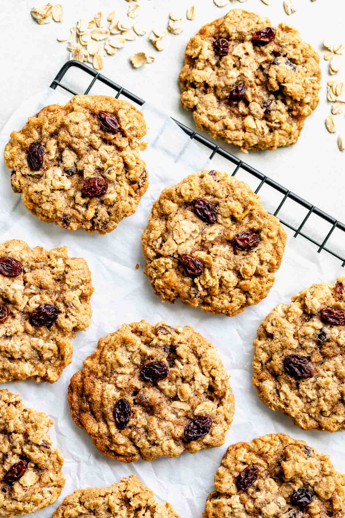 close up photo of whole wheat oatmeal raisin cookies cooling on parchment paper over a wire rack