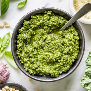 overhead photo of homemade kale pesto in circular black dish with a spoon