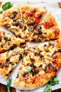 overhead photo of sliced pizza with mushrooms on cutting board