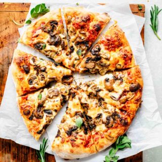 overhead photo of sliced pizza with mushrooms on cutting board