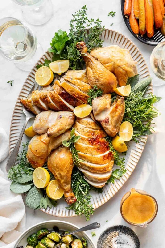 the carved roasted chicken on a platter with herbs