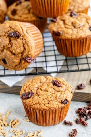 Closeup of one brand muffin on a white counter with several others on a cooling rack in the background