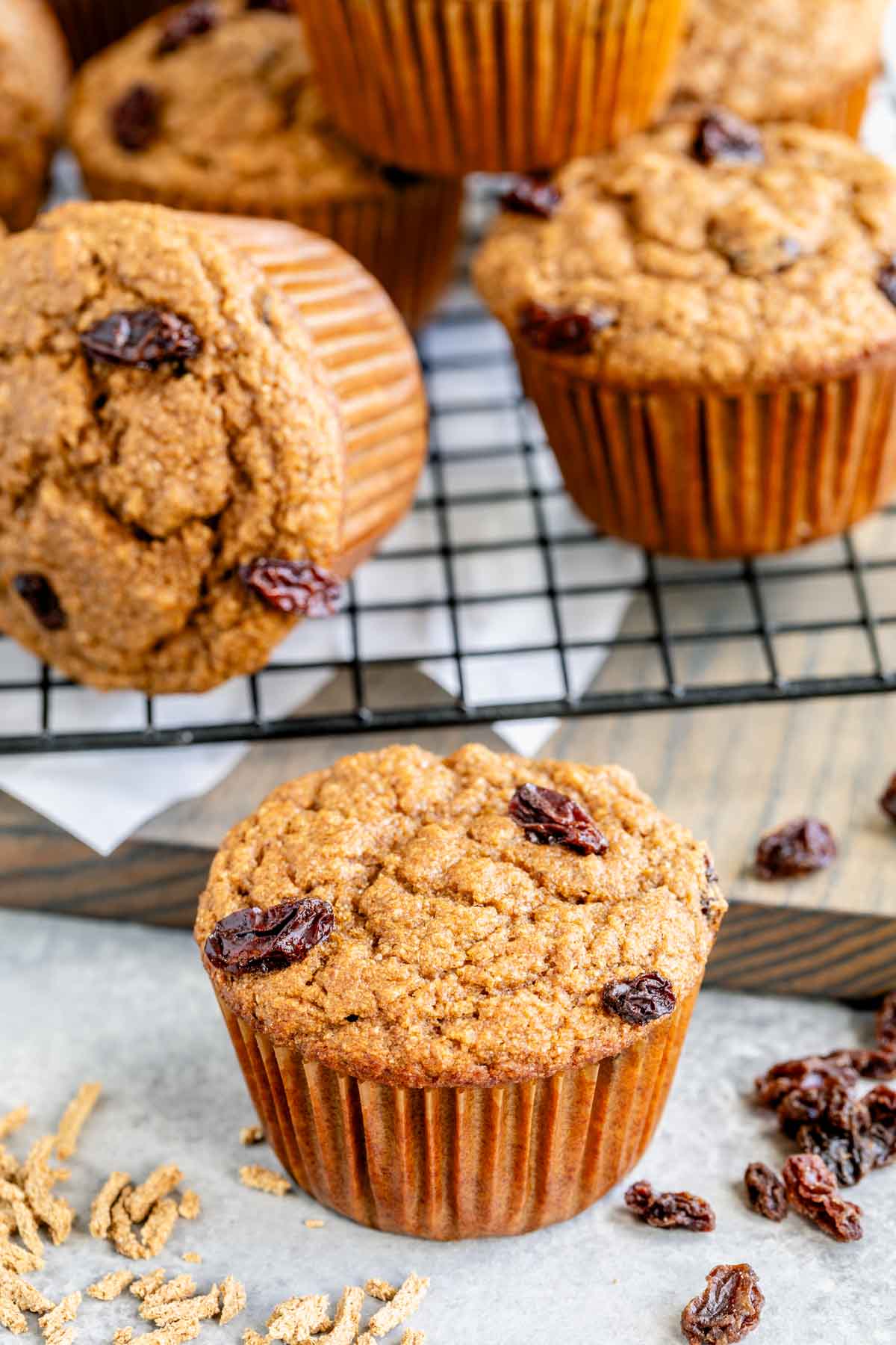 Closeup of one brand muffin on a white counter with several others on a cooling rack in the background