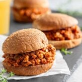 three ground turkey sloppy joes with a glass of orange drink out of focus on the left