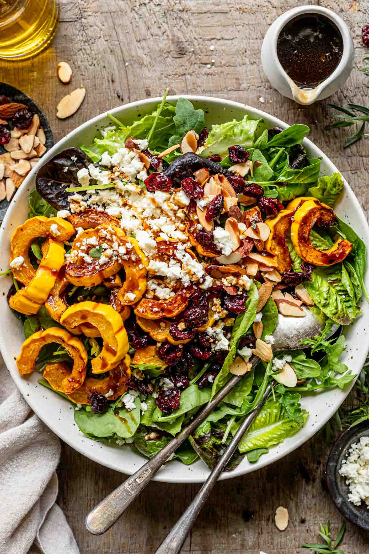 balsamic maple salad dressing poured over a simple green salad with delicata squash