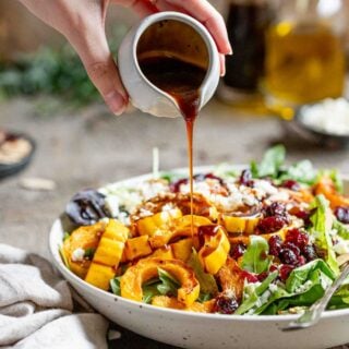 maple balsamic salad dressing being poured over a simple salad