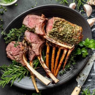 rack of lamb with herbs on a black platter