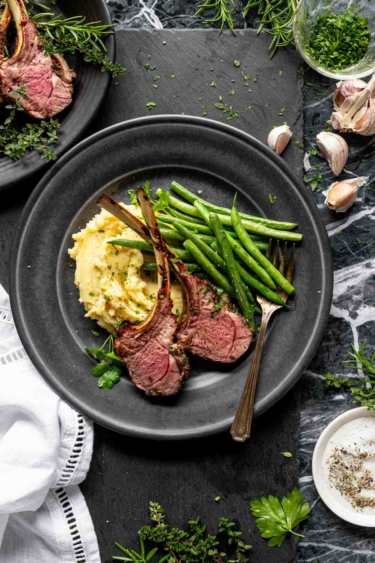 the rib chops on a black plate with green beans and mashed potatoes
