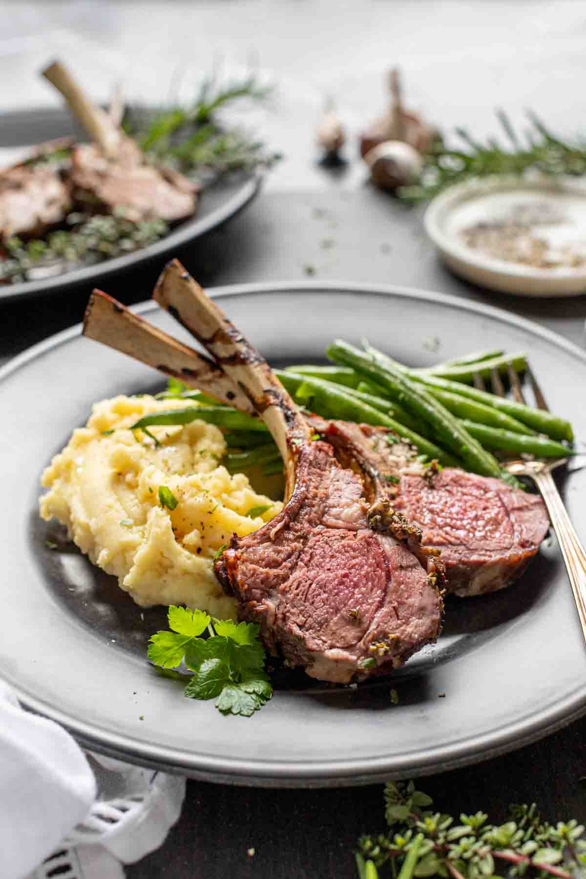 holiday table with plates of lamb chops with green beans and mashed potatoes