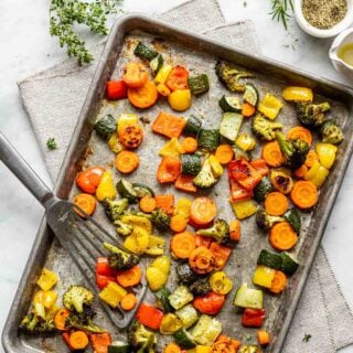 roasted veggies on a sheet pan with a spatula leaning on the dish