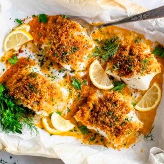 four pieces of cod in a baking dish with panko on top, lemon and herbs