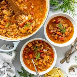 a large bowl of cabbage soup on the left top corner with two smaller bowls of soup to the right