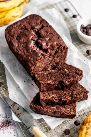 healthy chocolate banana bread beginning to be cut into slices with half of the loaf remaining