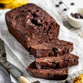 a loaf of whole wheat chocolate banana bread with half of it cut into slices