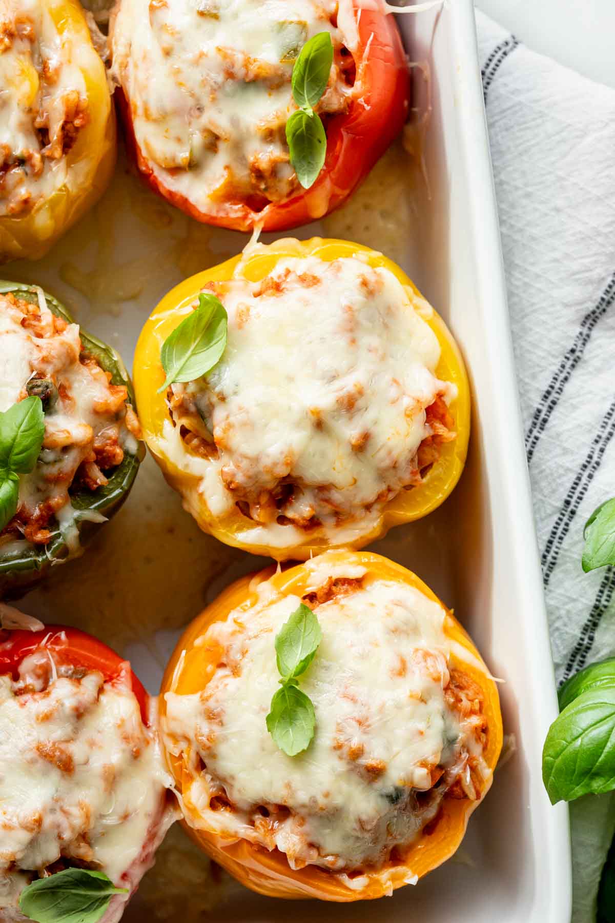 the stuffed peppers from overhead with melted cheese on top and basil garnish