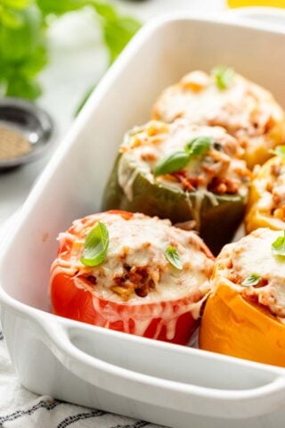 closeup side view of the red, yellow and green stuffed peppers with cheese melted all over them