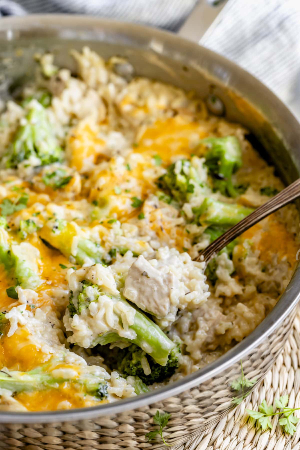 the one pan chicken and broccoli recipe in a straight sided skillet with spoon scooping into frame