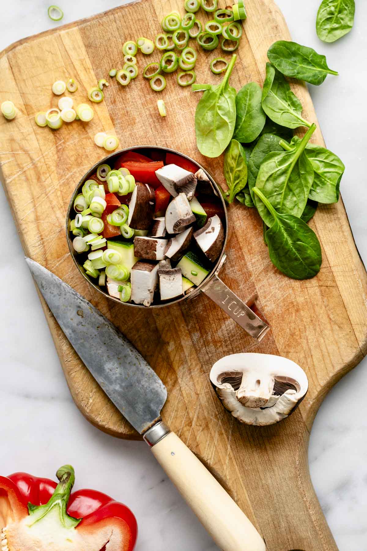 chopped veggies and baby spinach on a cutting board