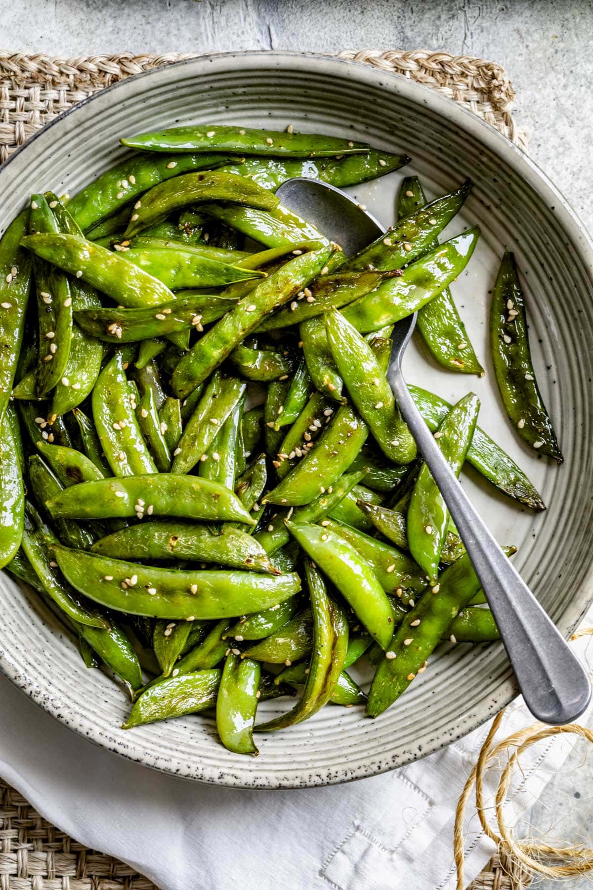 the roast snap peas in a serving bowl with a large spoon
